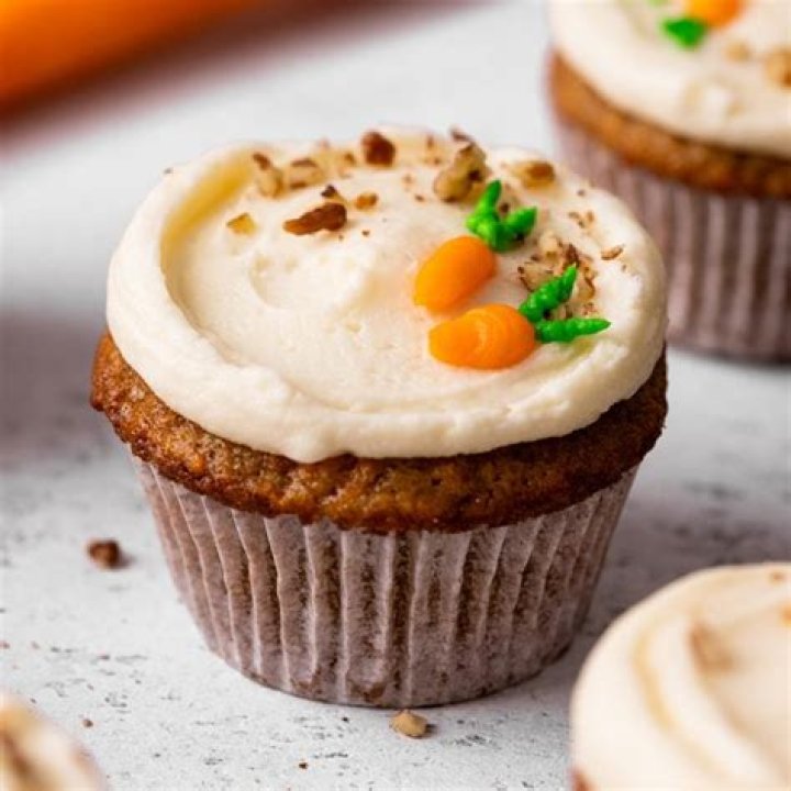 Carrot cake cupcake cut in half on a grey plate.